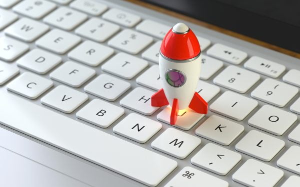 Toy rocket ship sitting on top of computer keyboard